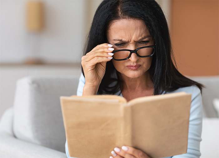 Woman squinting while reading a book